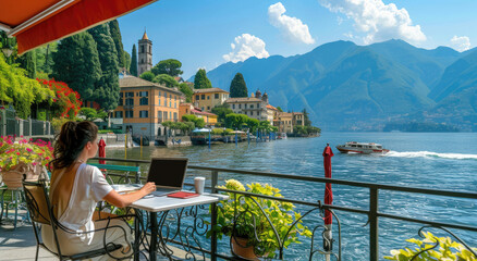 woman working on laptop in front of Lake Como, Italy, with mountains and buildings in the background, wearing sunglasses and white shirt