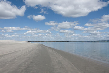 beautiful deserted sandy beach at West Wittering West Sussex England with blue sky and clouds reflecting in the sea