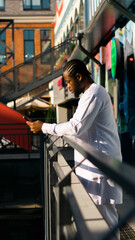 African American hipster guy in cultural and ethnic clothing dashiki chatting on smartphone...