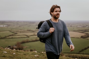 Man wearing long sleeve shirt, walking on hill