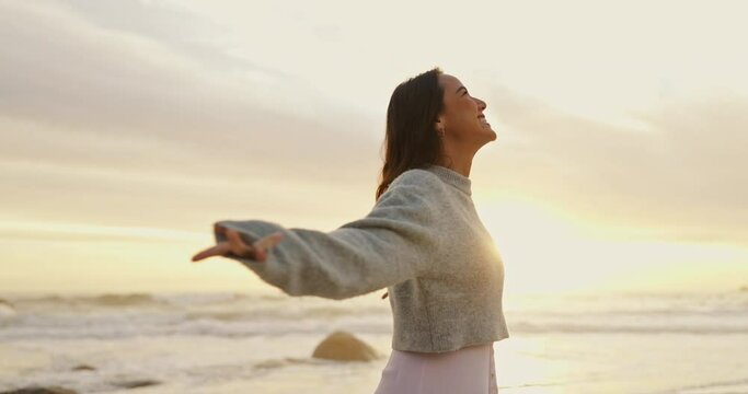 Ocean, sunset and woman with smile for freedom in vacation, weekend holiday and journey in California. Summer, female person and happy with raised hands in beach for fresh air or peace outdoors - Powered by Adobe