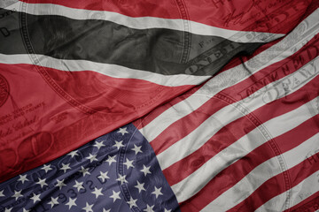 waving colorful flag of united states of america and national flag of trinidad and tobago on the...