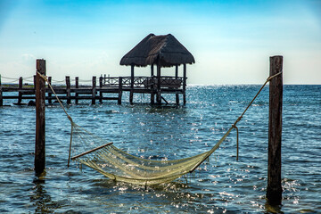 Hammock on the Caribbean Sea and a wooden dock and palapa in the background typical of this...