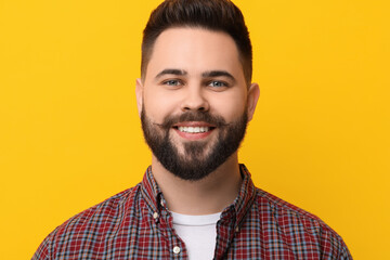 Portrait of happy young man with mustache on yellow background