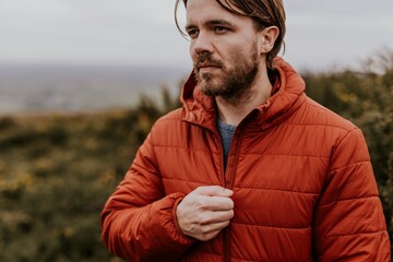 Man wearing orange puffer jacket, walking on hill © Rawpixel.com