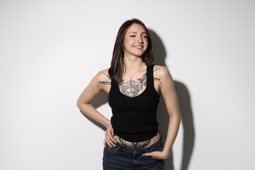 Portrait of smiling tattooed woman on light background
