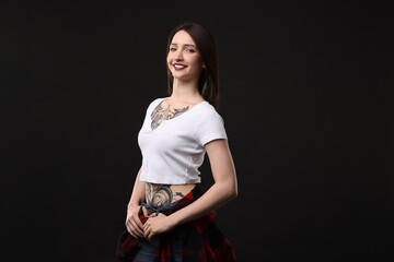 Portrait of smiling tattooed woman on black background. Space for text