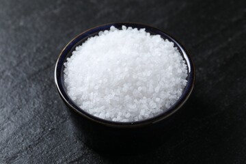 Organic white salt in bowl on black table