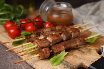 Tasty cooked marinated meat served with sauce and tomatoes on table, closeup