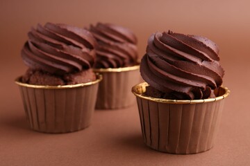 Delicious chocolate cupcakes on brown background, closeup