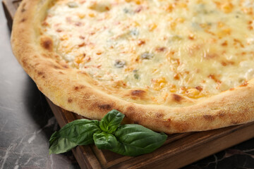Delicious cheese pizza and basil on black marble table, closeup