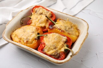 Delicious stuffed peppers in baking dish on white textured table