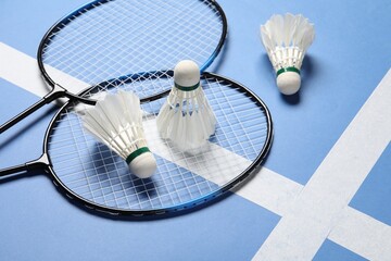 Feather badminton shuttlecocks and rackets on blue background