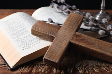Cross, Bible and willow branches on wooden table, closeup