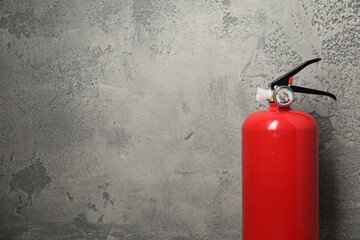 Fire extinguisher on grey textured background, space for text