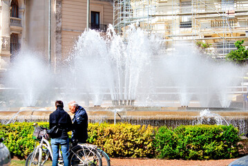 City fountain in a cityscape in the heat with people.Clouds of splashes, drops, jets of a fountain