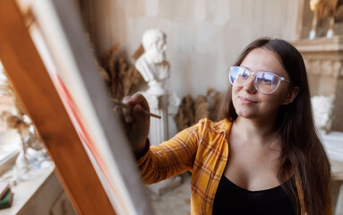 Girl artist paints a picture in a beautiful studio. 