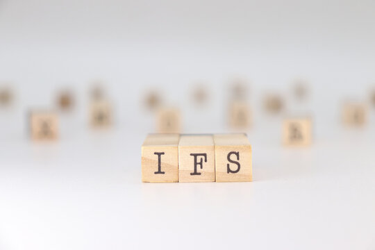 IFS acronym. Concept of Internal Family Systems written on wooden cubes isolated on white background