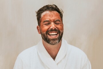 Obraz premium Laughing man in robe with facial mask isolated on background