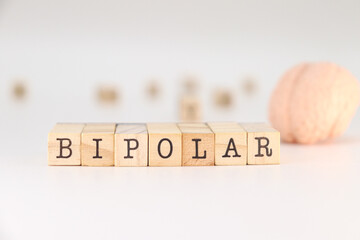 Bipolar word written on wooden cubes isolated on white background with blurred brain. Text concept...