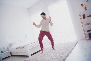 Photo of cheerful positive good mood glad man wearing stylish nightwear dancing floor enjoying...