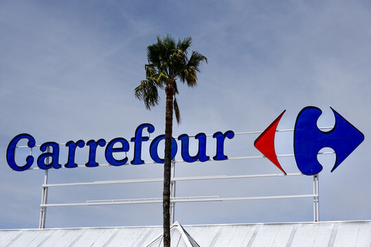 Finestrat, Spain - April 9, 2024: Carrefour logo sign on Carrefour supermarket on sky background. Carrefour is French multinational retail and wholesaling corporation