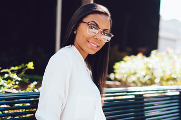 Portrait of happy attractive african american young woman in stylish eyeglasses and trendy white...