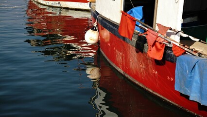 side reflection of humble boat on the harbor water
