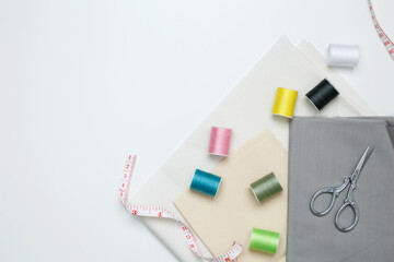 Composition with various threads and sewing accessories on white background