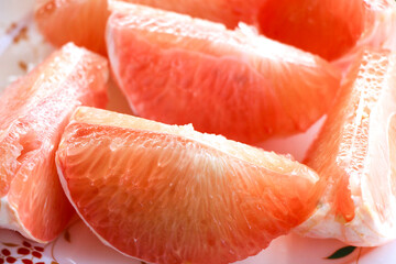 A plate with sliced pomelo or grapefruit, isolated.