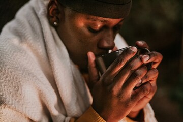 Man keeping warm with hot chocolate, a beanie, and a shawl