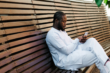 Millennial generation african american man typing sms outdoor 5g internet concept. High speed internet on phone and chatting on social networks and blog concept