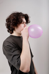 caucasian boy inflating a balloon in studio