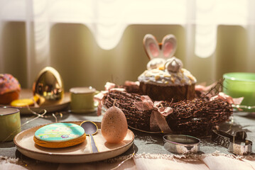 Easter decoration of colorful eggs in a basket and a rabbit on the kitchen table in a rustic style. Festive interior of a country house