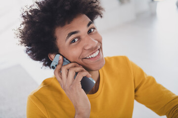 Photo of young cheerful man speaking phone working white light interior room indoors