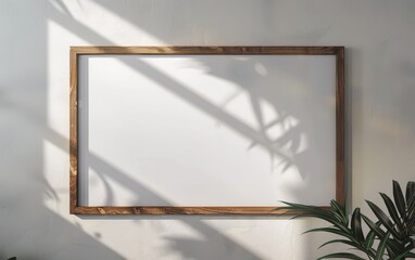 A white framed picture with a plant in the background