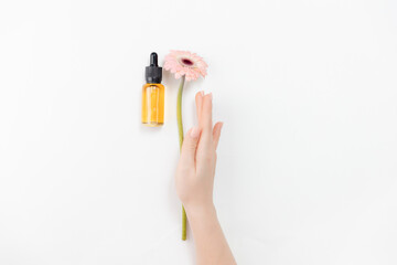 Beauty womans hands with manicure hold serum oil and pink flower on white background, place for...