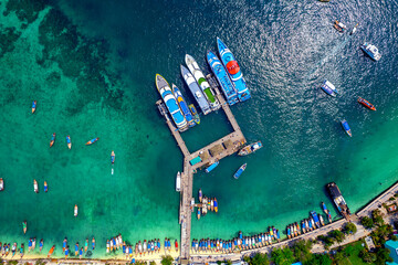 Aerial top view pier with thai long tail boat and taxi yacht in turquoise sea. Phi Phi Island, Thailand