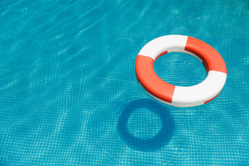 Red lifebuoy in blue water of pool, top view. Emergency help of bank system concept