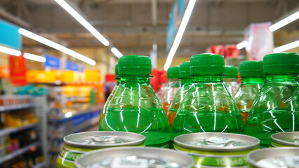 Close-up of many green soda bottles in a supermarket