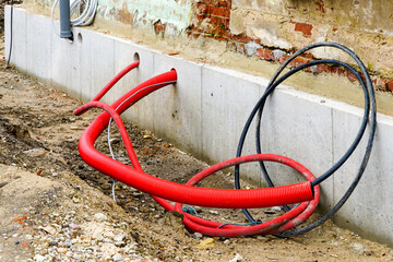 Thermally insulated foundations of an old brick house with passing communication cables and pipes