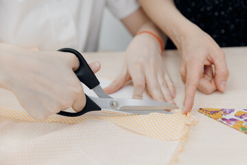 Dressmaker girl child cutting fabric with scissors on sewing master class in school
