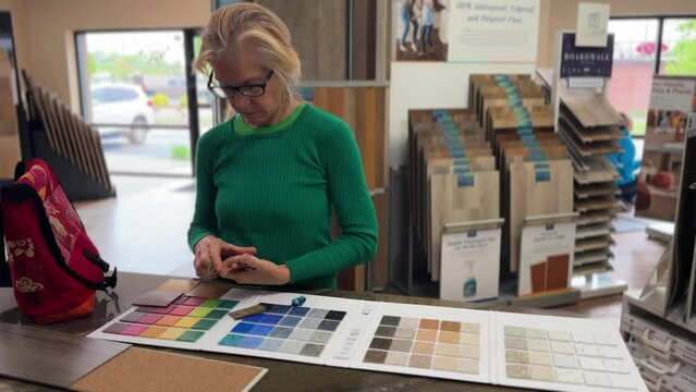 Female interior designer or architect choosing color sample from swatch board in design studio. Floor and wall finishing material for architecture and construction industry.