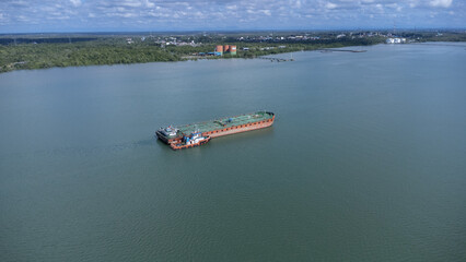 An oil tanker is parked in the Kalimantan sea with a beautiful backdrop of mountains and clouds