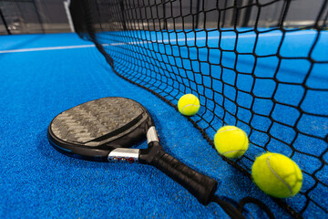 balls near the net of a blue padel tennis court