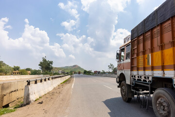 Landscape of Indian national highways with heavy vehicles running o it surrounded by aravalli hills under the blue sky. National highways connected different cities and also saves time and fuel.