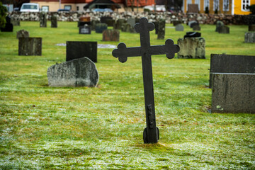 Leaning metal cross on a grave yard.