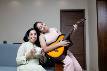 Young Teen Girl with Mother and home playing Guitar and enjoying the moment with mother at home
