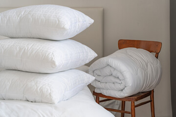 A bed with white pillows and a blanket, next to a bedside table with a lamp, daylight