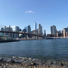 Naklejka premium View of New York City from the riverfront in Dumbo, Brooklyn, showcasing iconic skyscrapers and the city skyline against the backdrop of the East River